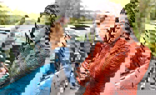 Two people in a fender bender on their phones, looking concerned