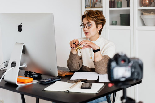 A woman sitting at a desk, using a computer and camera for work.